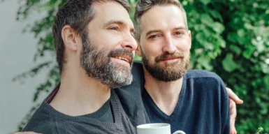 A gay couple enjoying a cup of coffee outdoors together.