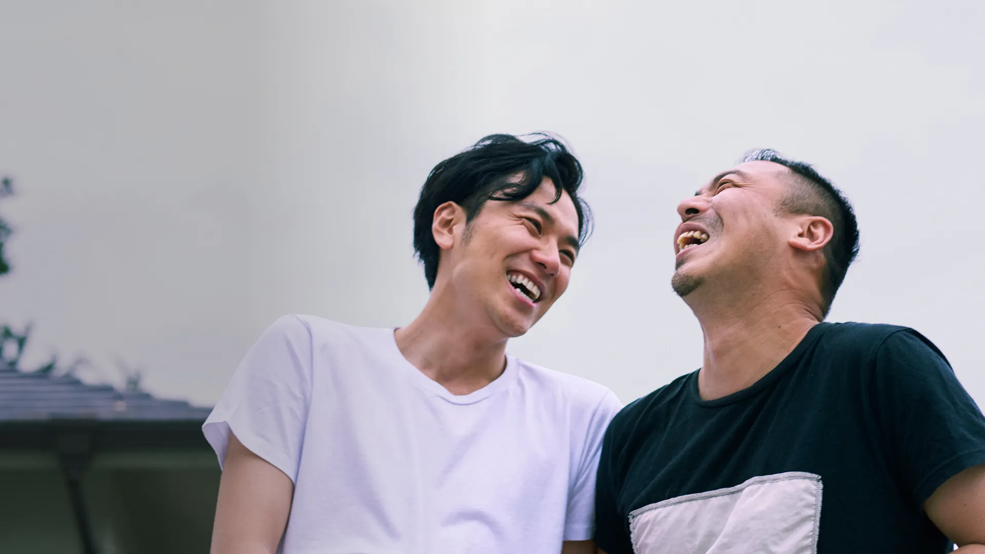 A gay Asian couple laughing together.