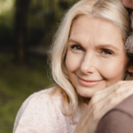 A woman leaning on a man's shoulder smiles at the camera as a symbol of how eharmony works