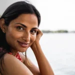 A indian woman is sitting next to a lake.